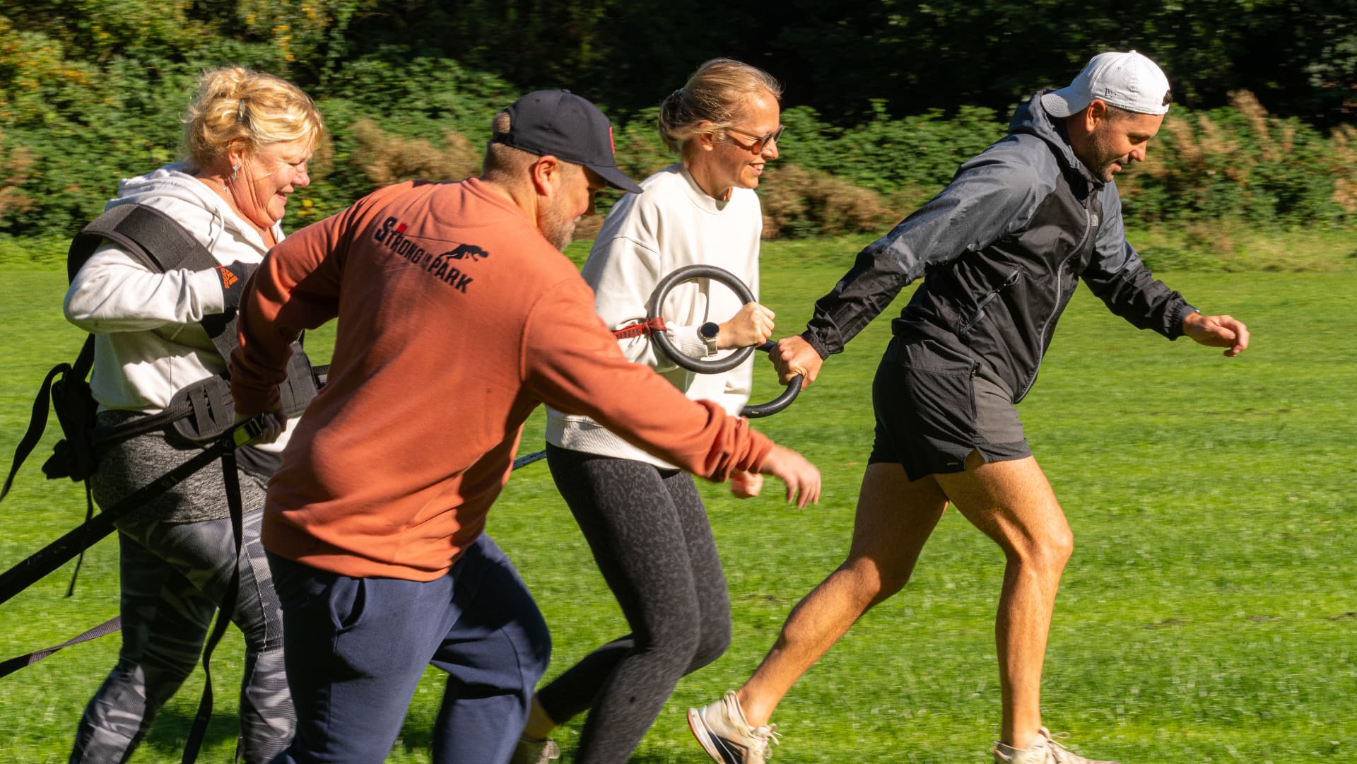 Four Strong in the Park members training together with resistance equipment on the grass