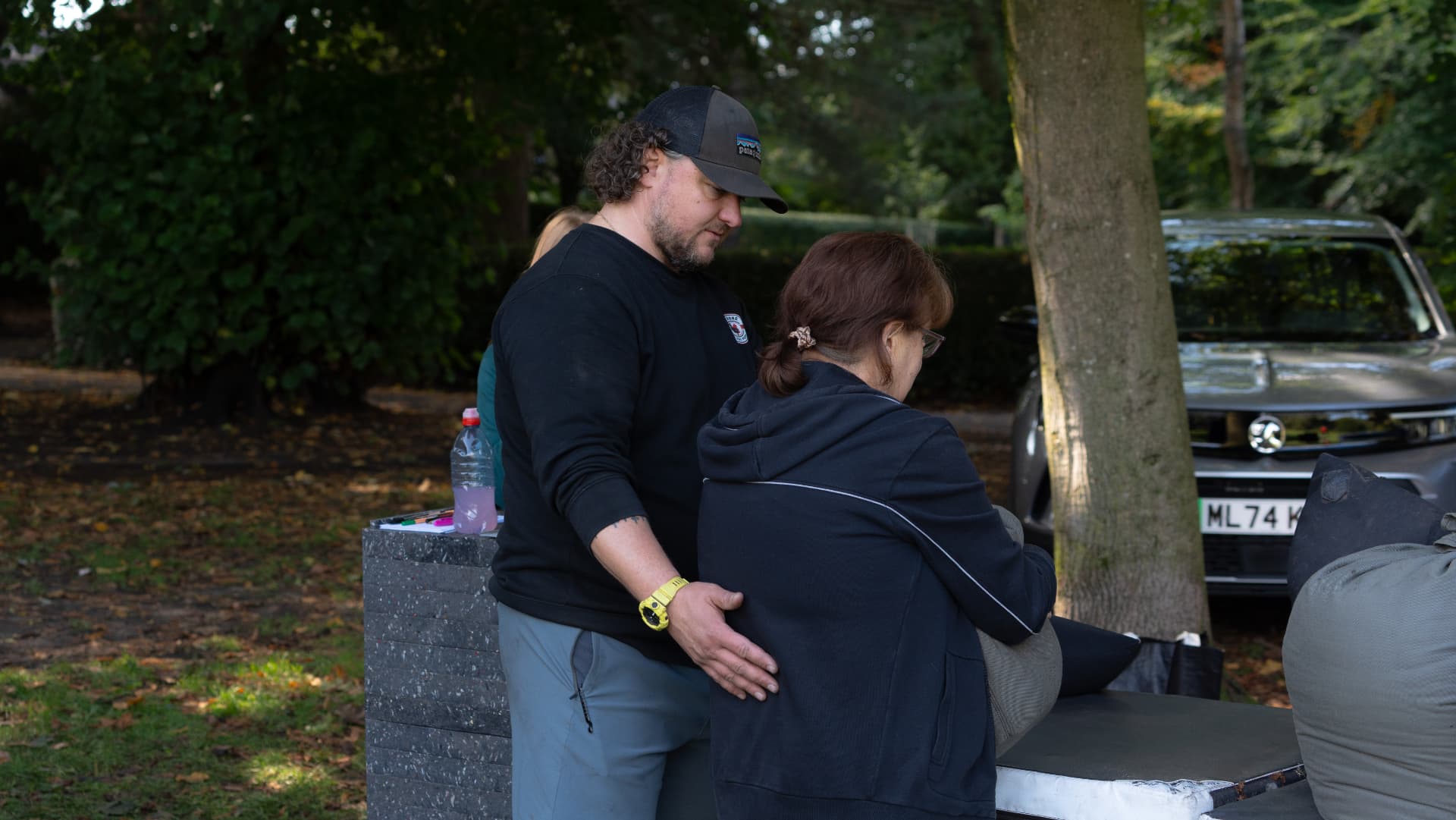 A coach supporting a member during outdoor strength training